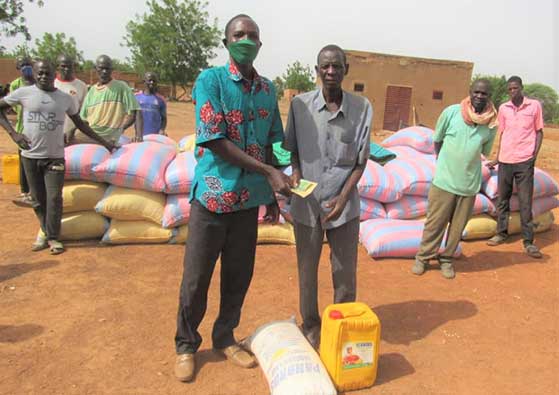 this man is receiving money donated to help him to grind corn he received.